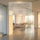 A high-impact feature photograph for a blog guide, based on a luxurious sun-drenched Dubai penthouse at sunrise. The monumental fluted glass pivot door is open on the left, frameless sliding glass is in the center-back, and a framed hinged glass door is to the home office on the right. An elegant frosted glass overlay in the upper-center frame is integrated, with etched, minimalist typography reading: 'THE ULTIMATE GUIDE TO GLASS PARTITION DOORS' (larger), followed by 'SLIDING, PIVOT, AND SWING' (smaller), and 'PUBLISHED BY MAJLIS HIKMA ALUMINIUM & GLASS LLC' below, all illuminated by the warm golden light. The overall perspective emphasizes expansive luxury, clarity, and spatial flow.